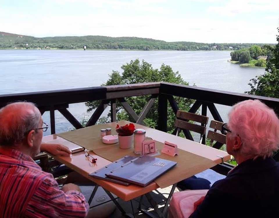 Frau Bohn begleitet ein älteres Paar bei einem Ausflug mit Blick auf das Wasser